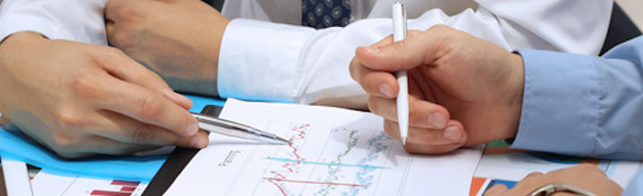 Office workers pointing pens at a graph on a table